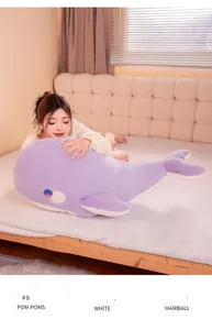 Close-up detail of a soft purple whale plush pillow being hugged by a woman on a bed