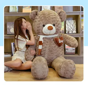 Giant brown teddy bear plush toy sitting with a model to show its massive scale