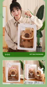 Detalle de un lindo peluche de carpincho con una elegante bolsa de regalo blanca