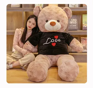 Close-up of a giant plush teddy bear wearing a black Love shirt next to a model