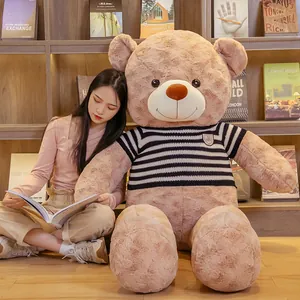Giant teddy bear plush toy wearing a striped sweater sitting in a cozy home library