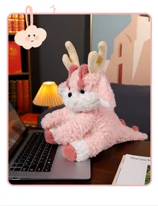 Adorabile peluche di drago rosa seduto su un laptop in un accogliente ufficio in casa.