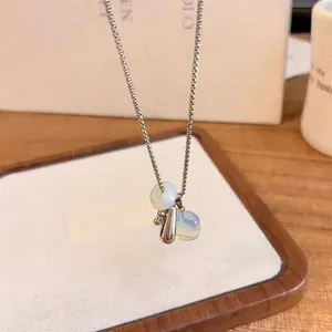 Detail showing the silver box chain and the translucent natural stone drop pendant of the necklace.