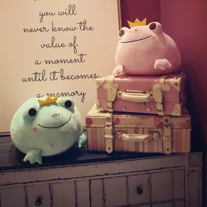 Soft pink and green crown frog plush toys beautifully styled on vintage suitcases and dresser.