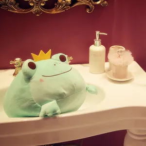 Soft crown frog plush toy displayed in a white bathroom sink for aesthetic home decor