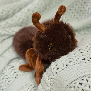 Süßes braunes flauschiges realistisches Ameisen-Plüschtier auf einer grünen Strickdecke