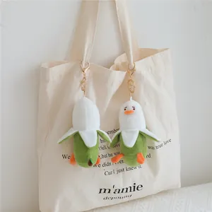 Close-up detail of banana duck plush keychain hanging on a minimalist cream canvas bag