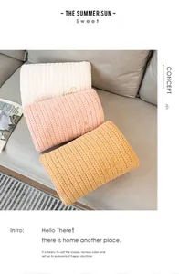 Three soft knitted hand warmer pillows in cream pink and orange on a cozy sofa