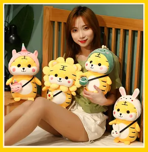 Asiatisches Model mit weichen Tiger-Plüschtieren in Tierkostümen im Bett