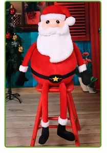 Langbeiniger Weihnachtsmann aus Plüsch sitzt auf einem roten Hocker in einem Raum.