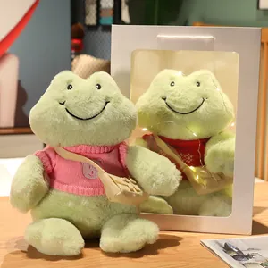 Peluche de rana verde sonriente con suéter rosa en una bonita caja de regalo blanca