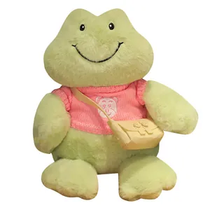 Linda rana de peluche verde sonriente con un suéter rosa y un pequeño bolso cruzado