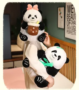 Detailed close-up of soft panda plush toys with pink bow and boba cup in a cozy room
