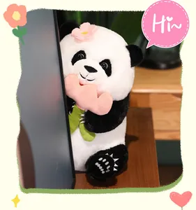 Close-up of a cute panda plush toy with a pink flower behind a computer monitor
