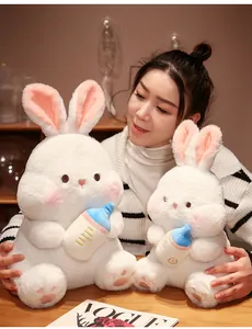 Detailed view of soft white rabbit plush dolls with baby bottles held by an Asian model