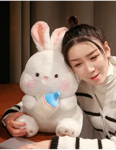 Soft white bunny plush toy with a blue feeding bottle shown with a young model
