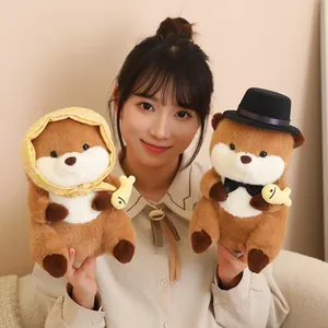 Adorable otter plush toy set featuring hat and headscarf, held by an Asian model in indoor setting