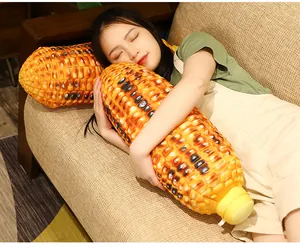 Large realistic roasted corn cob plush pillow shown in a lifestyle scene on a sofa