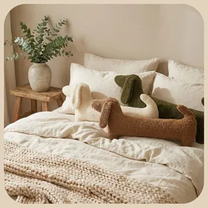 Coussins en peluche longs en forme de teckel de trois couleurs sur un lit très confortable