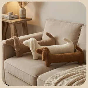 Coussins teckel en peluche marron et crème sur un canapé beige dans un décor douillet
