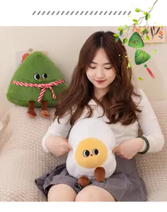 Primo piano di simpatici peluche a forma di tuorlo d'uovo e zongzi tenuti da una modella