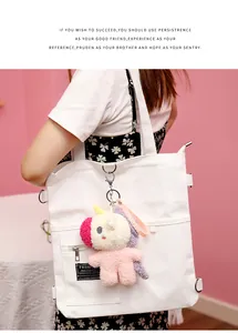 Cute plush unicorn bunny bag charm accessory hanging on a white canvas tote bag detail