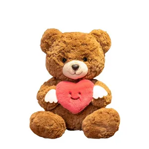 Süßer brauner Plüsch-Teddybär hält ein rosa Herz mit Flügeln als Valentinsgeschenk