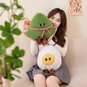 Simpatici peluche a forma di Zongzi e uovo tenuti da una modella in una stanza accogliente.