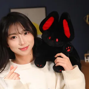 Adorable black flying bat rabbit plush toy with red accents held by a smiling model.