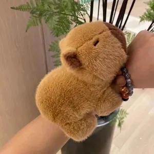Adorable bracelet claque en peluche capybara marron porté au poignet d'une personne.