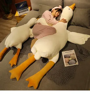 Détail d'un grand oreiller en peluche d'oie blanche serré dans ses bras sur un lit