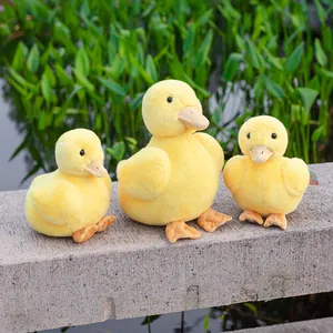 Set of three soft yellow duck plush toys in various sizes on stone ledge