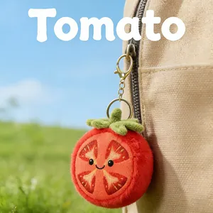 Cute plush tomato keychain charm hanging on a beige canvas backpack outdoors.