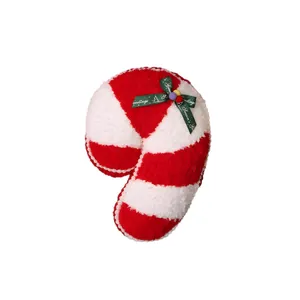 Coussin en peluche canne de Noël rouge et blanc avec un ruban vert festif.