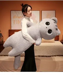 Giant gray long cat plush pillow held by a model in a cozy bedroom setting
