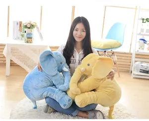 Detailed view of soft large blue and yellow plush elephant pillows held by a model in a room.