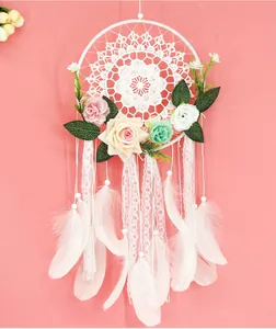 Vue détaillée d'un attrape-rêves en dentelle blanche avec roses pastel et plumes.