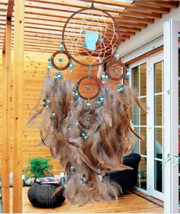 Handmade brown feather dreamcatcher decoration with blue beads hanging on a patio