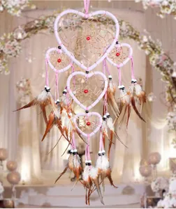 Close-up detail of a pink heart-shaped five-ring dream catcher with natural brown feathers