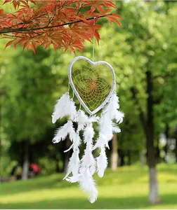 Pure white heart-shaped dream catcher with feathers hanging on a tree branch