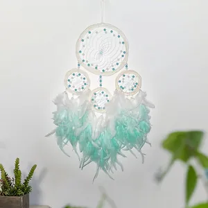 Detail view of mint green and white feathers on a handcrafted four-ring rattan dreamcatcher