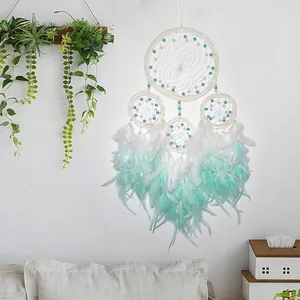 Detail of a four-ring dreamcatcher with mint green and white feathers for home decor.