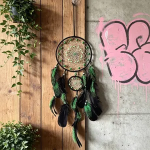 Acchiappasogni boho fatto a mano con perle verdi e piume nere appeso al muro