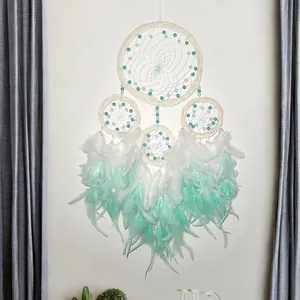 Detailed view of a handmade mint green and white four-ring dreamcatcher with rattan hoops.