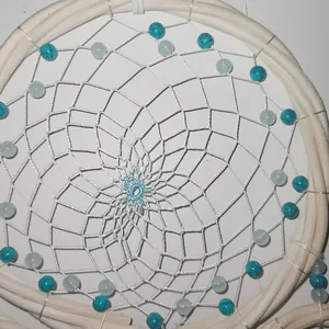 Macro detail of a white rattan dream catcher web with blue and turquoise beads