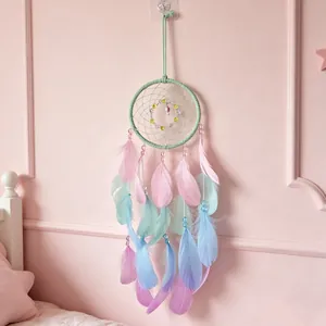 Pastellfarbener Traumfänger mit rosa-blauen Federn an rosa Schlafzimmerwand-Deko