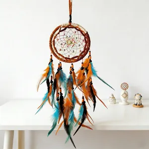 Detailed view of handmade dreamcatcher featuring vibrant orange and teal feathers