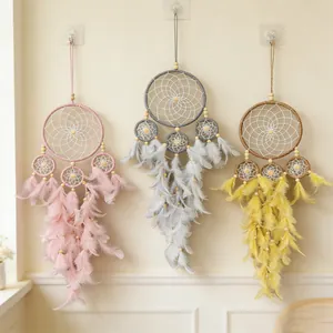Detailed view of handmade dream catchers with soft feathers in pink, grey, and yellow