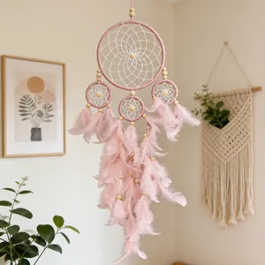 Handmade pink dreamcatcher with four rings and soft feathers hanging in a cozy room