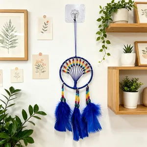 Handmade blue dreamcatcher with rainbow beads and vibrant feathers on a white wall
